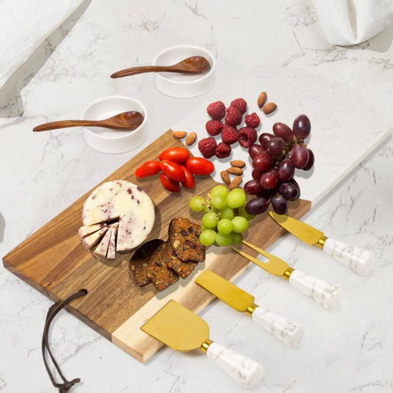 Marble and acacia wood charcuterie board set with 4 gold cheese knives, 2 wooden spoons, and 2 round ceramic sauce bowls.